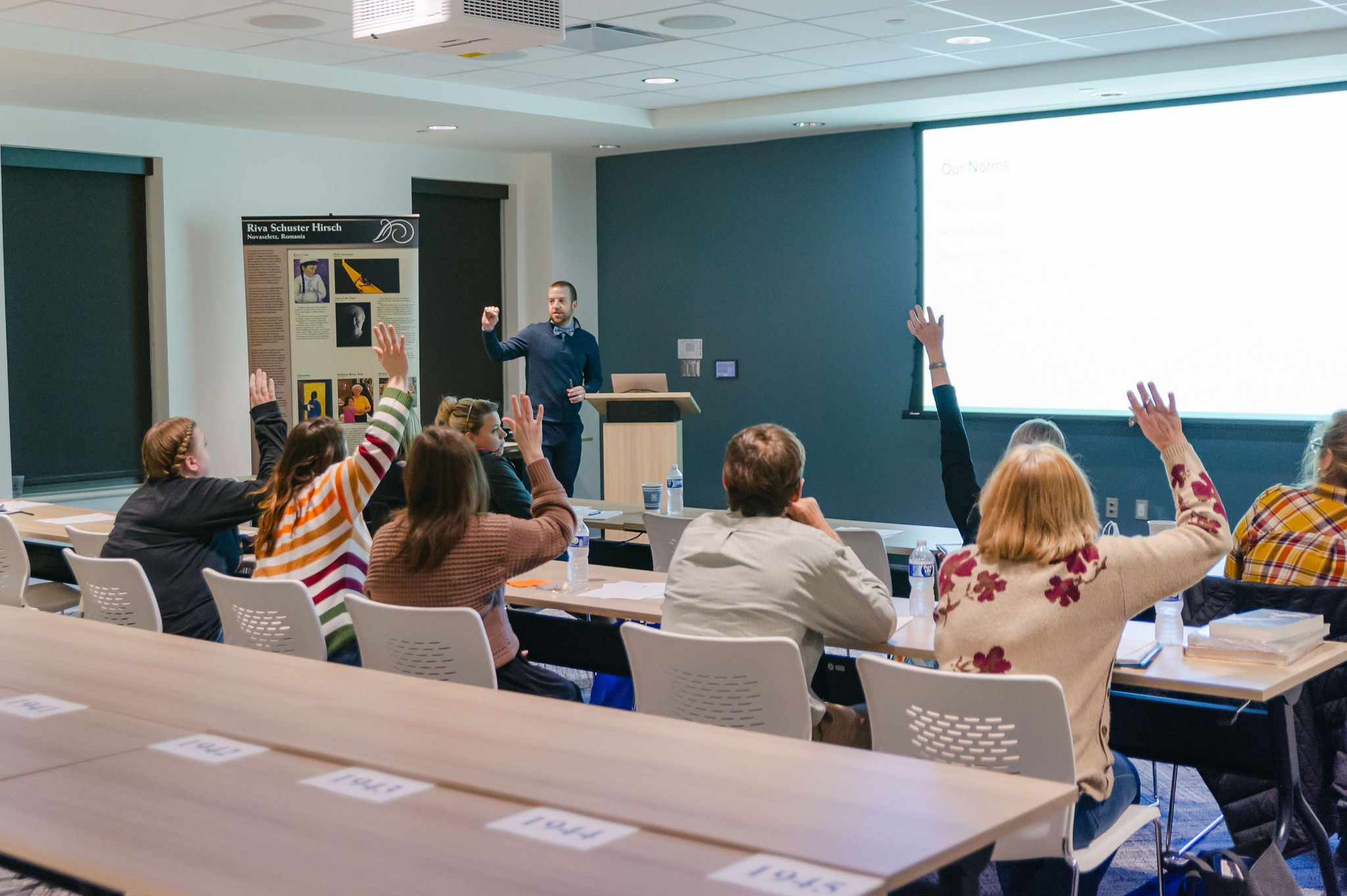 Man presenting powerpoint to students asking questions