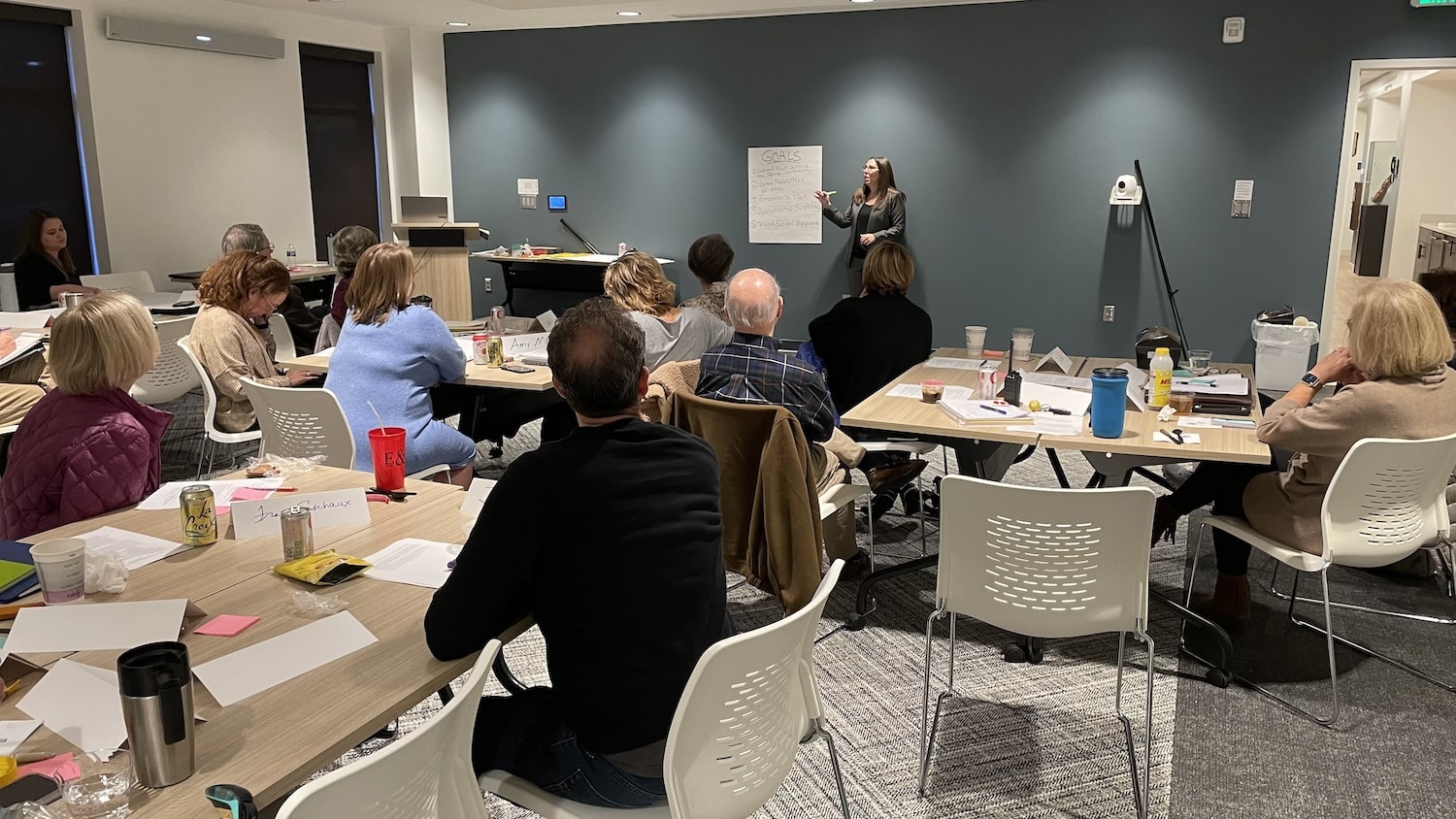 Woman speaking to class with adults sitting at table