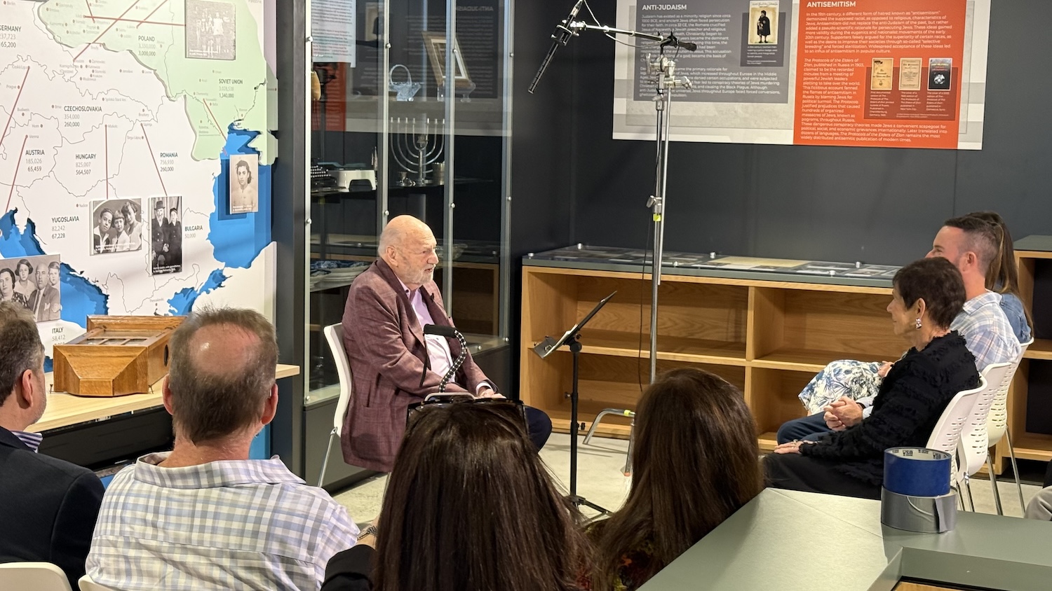 Survivor speaking to group in classroom with map